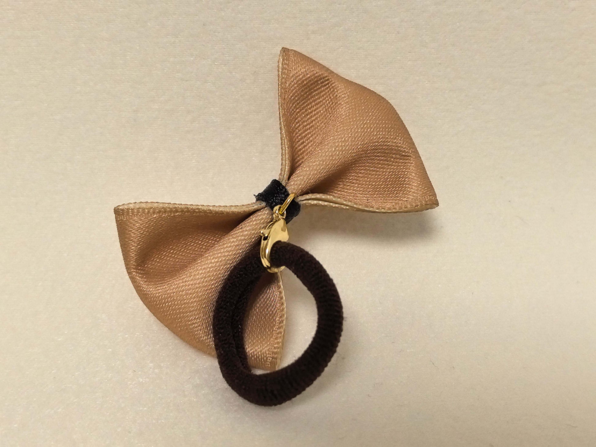 back view of a light tan (beige)  pet bow with a pink center, gold clasp, and attached dark brown hair tie. SilkyCo set.