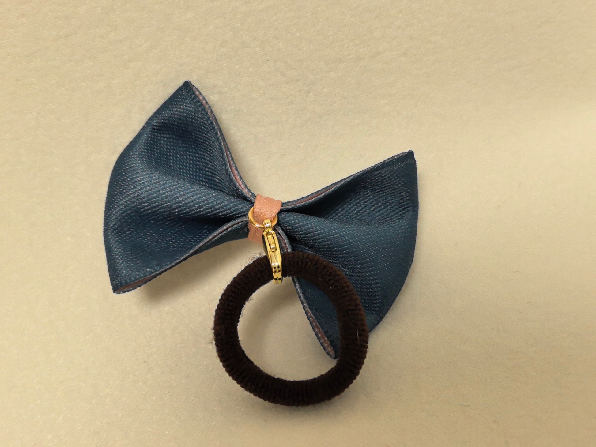 Back view of a pink bow with black trim, showcasing the sturdy gold clasp and integrated black elastic hair tie.