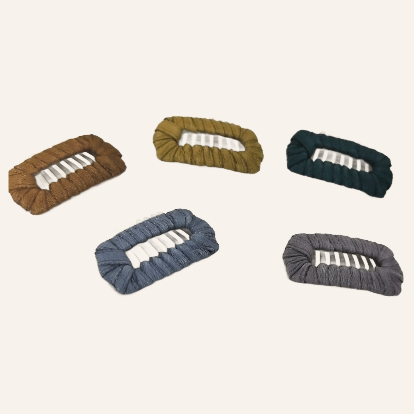 SilkyCo Hand-Wrapped Milk Silk Dog Barrettes in 5 colors: Dark Green, Khaki, Brown, Dusty Lavender, light Blue. The woven barrettes are laid out on a light background, showcasing texture and color variety.