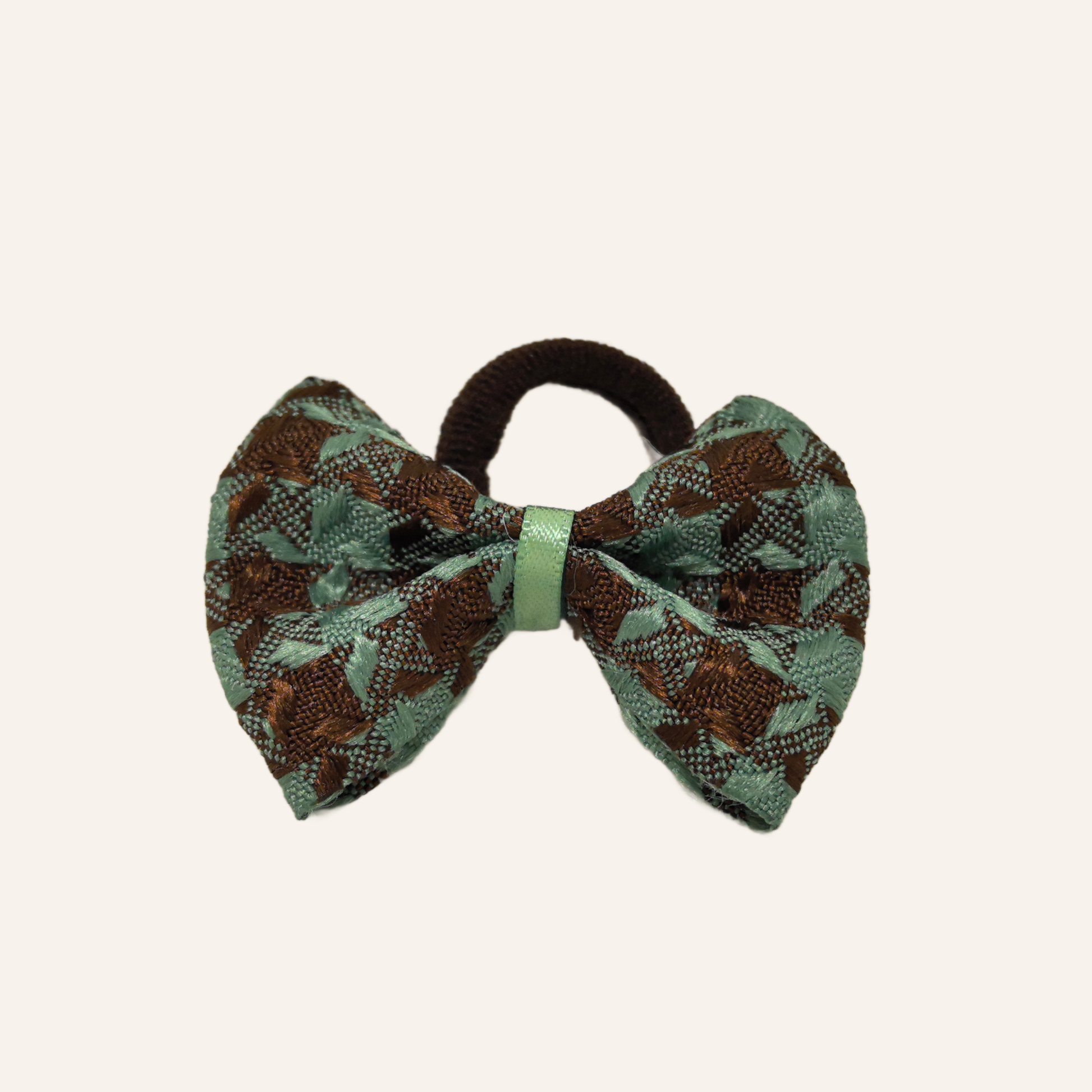 Close-up detail of the SilkyCo dog bow, highlighting the textured houndstooth weave, stitching, and light green securing ribbon