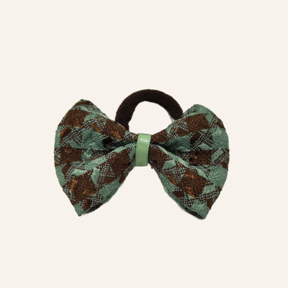 Close-up detail of the SilkyCo dog bow, highlighting the textured houndstooth weave, stitching, and light green securing ribbon